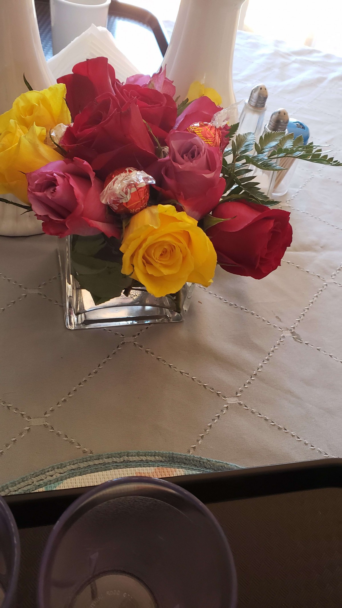 A vibrant bouquet of roses in a glass vase adorns a table with a decorative cover.
