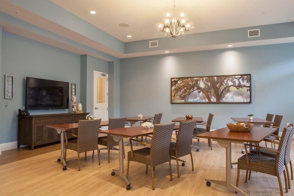 A modern conference room with tables and chairs, a television, and artwork on the wall.