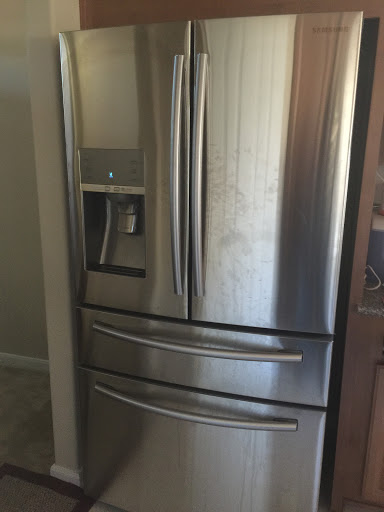 A sleek stainless steel refrigerator with French doors and a water dispenser.