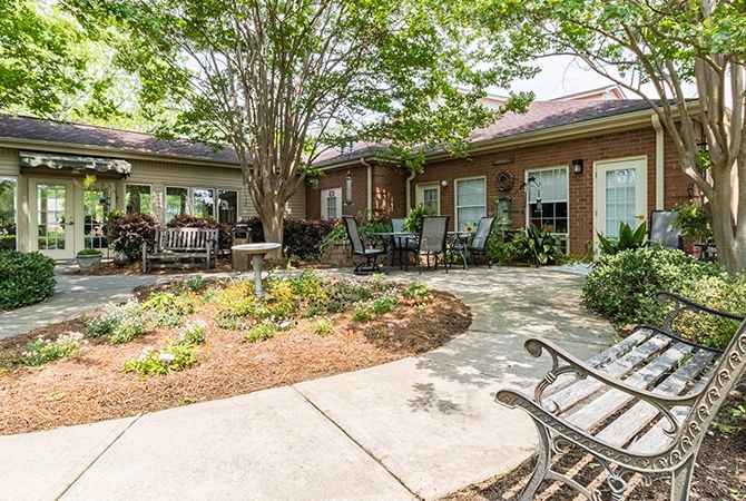 A peaceful courtyard with a garden and seating area surrounded by trees.
