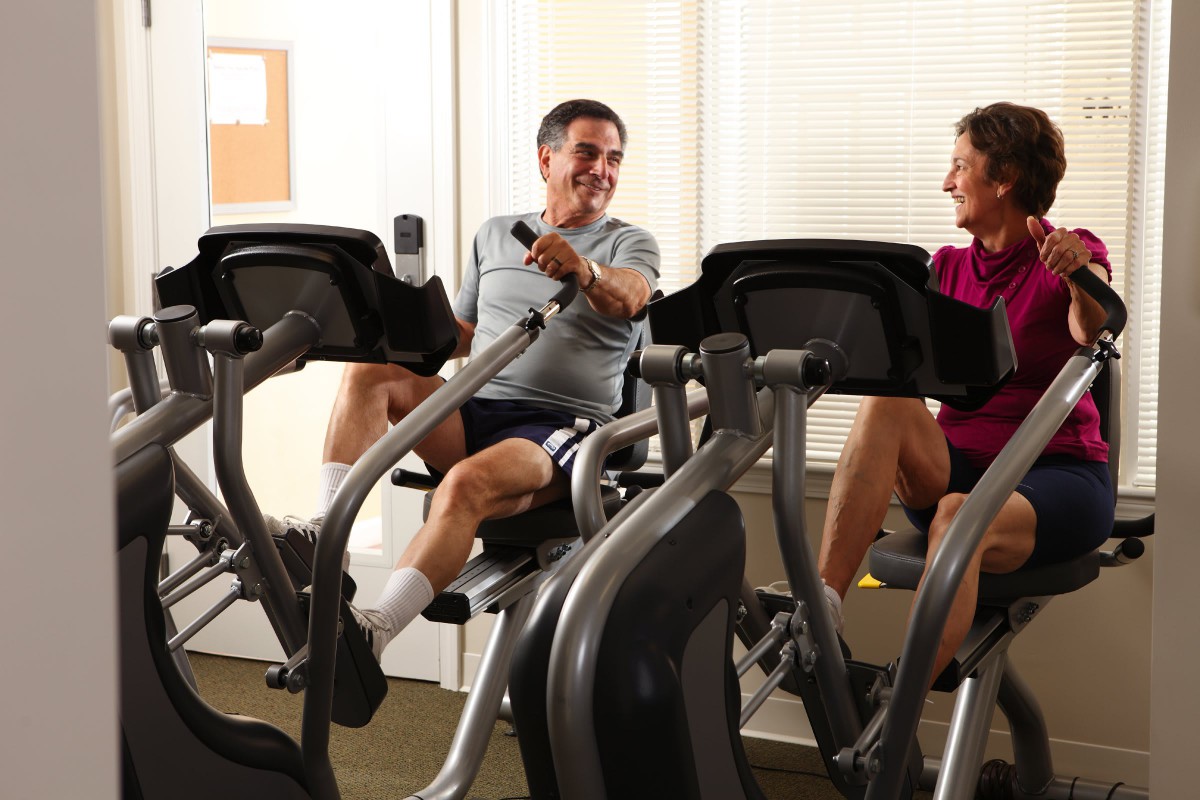 Two people exercising on stationary bikes in a gym.