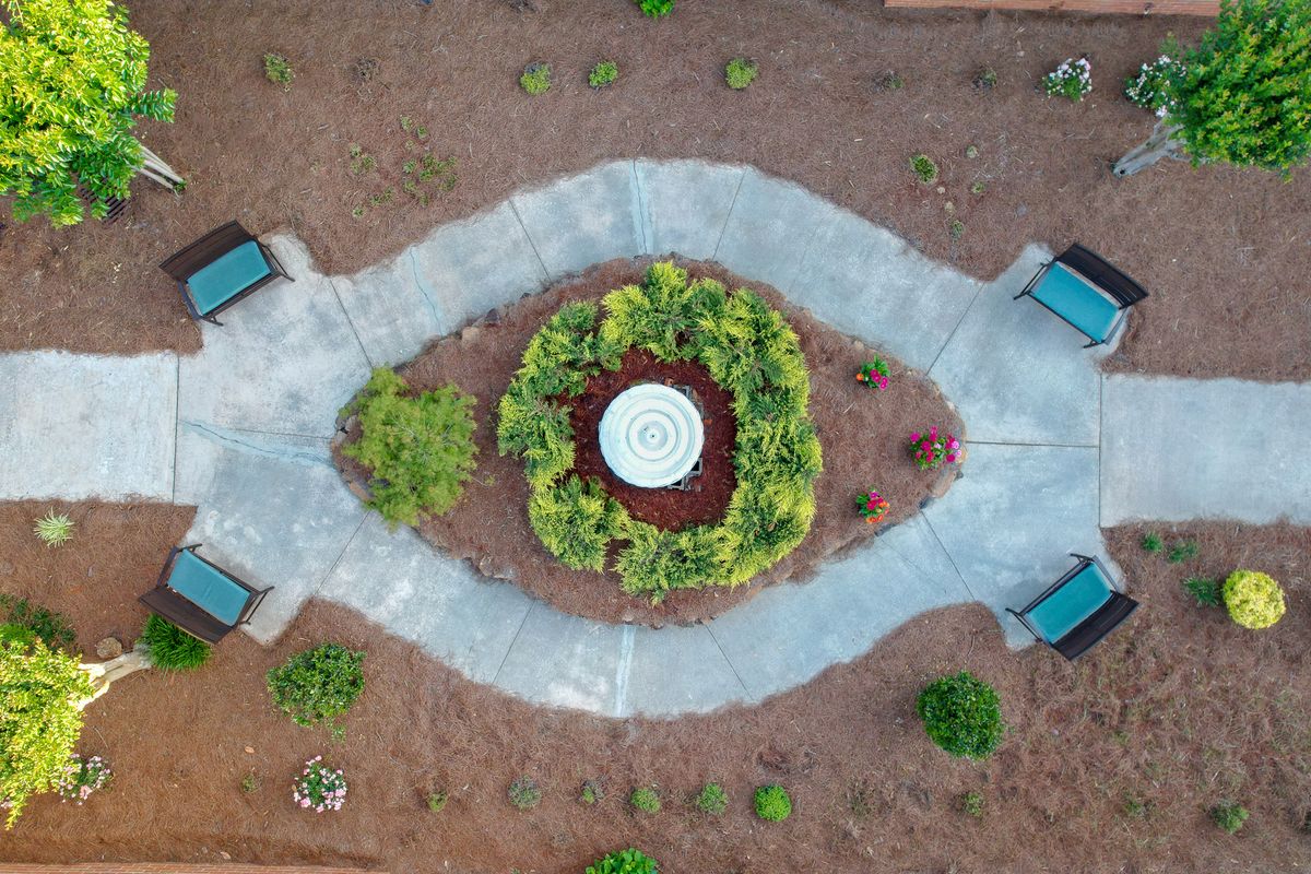 Aerial view of a symmetrical garden with pathways surrounding a central circular feature.