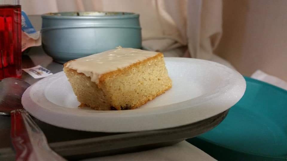 A slice of frosted cake on a white plate.