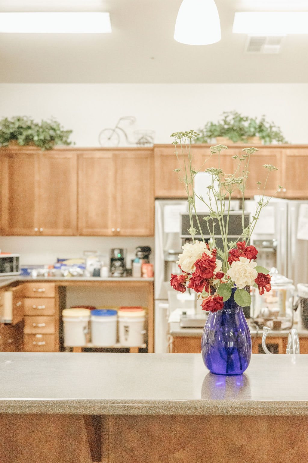 A cozy kitchen with a vibrant bouquet of flowers in a blue vase on the countertop.