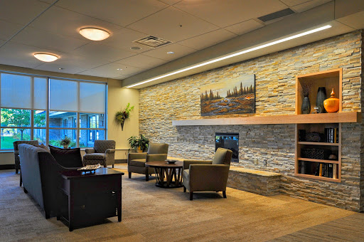 A welcoming and modern lounge area featuring comfortable seating, a stone accent wall, and a cozy fireplace.