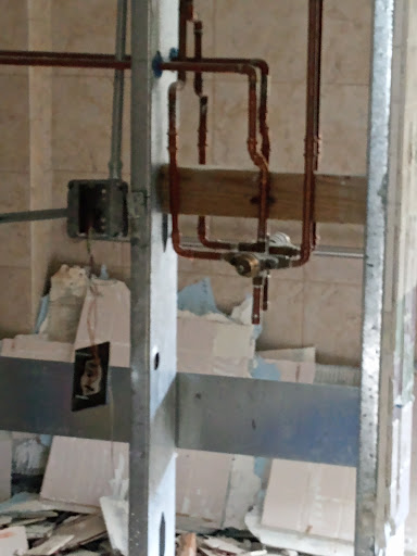 A close-up view of plumbing installation in a construction site, featuring copper pipes and metal supports.