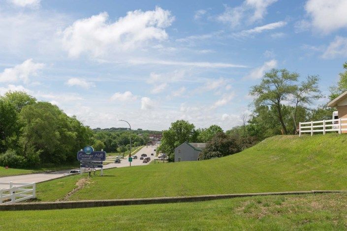 A scenic view of a road with traffic amidst lush greenery and a cloudy sky.