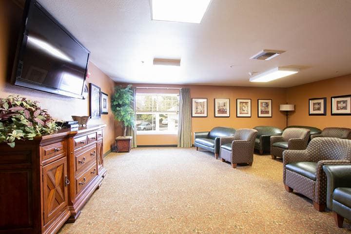 A cozy living room with sofas, a television, and decorative paintings.