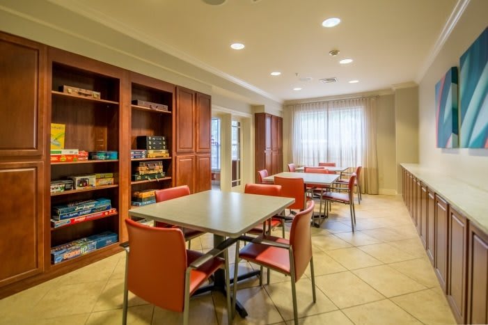 A cozy library room with tables, chairs, and bookshelves.