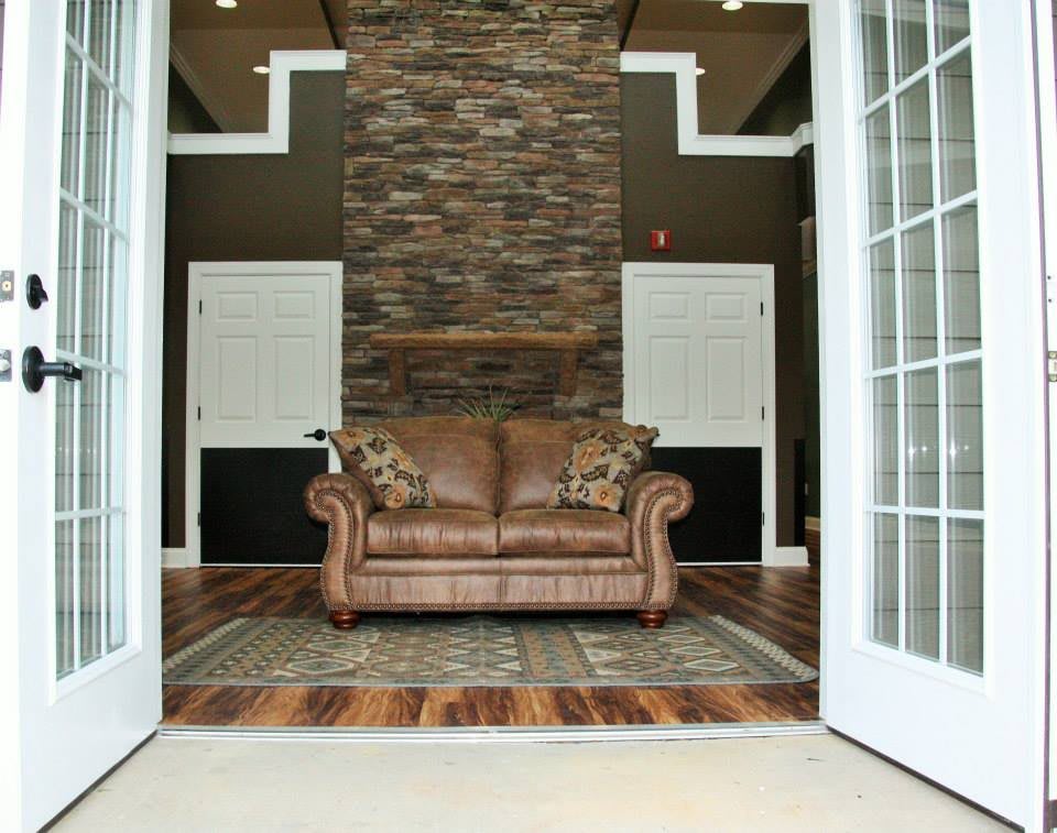 A stylish living room with a brown leather sofa centered between open double doors, showcasing modern interior decor.