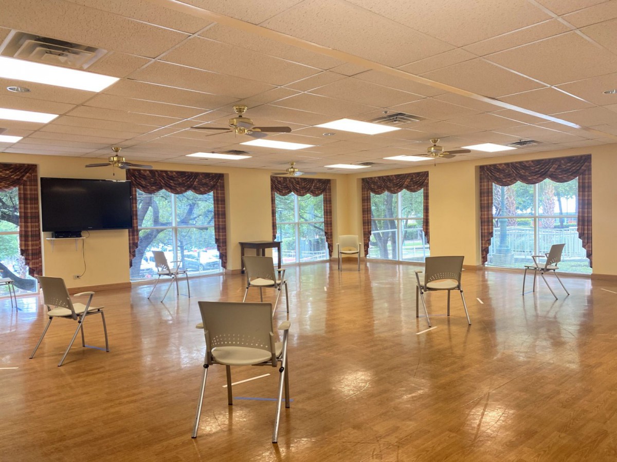 An indoor meeting space with chairs arranged apart and large windows overlooking greenery.