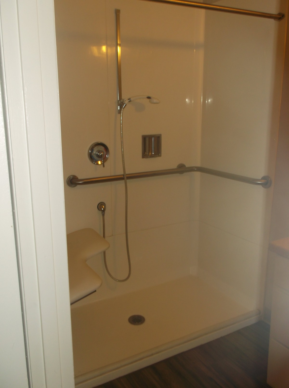 A bathroom shower with handrails and a showerhead.