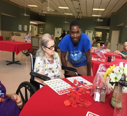 A volunteer interacts with a resident at a nursing home while playing bingo.