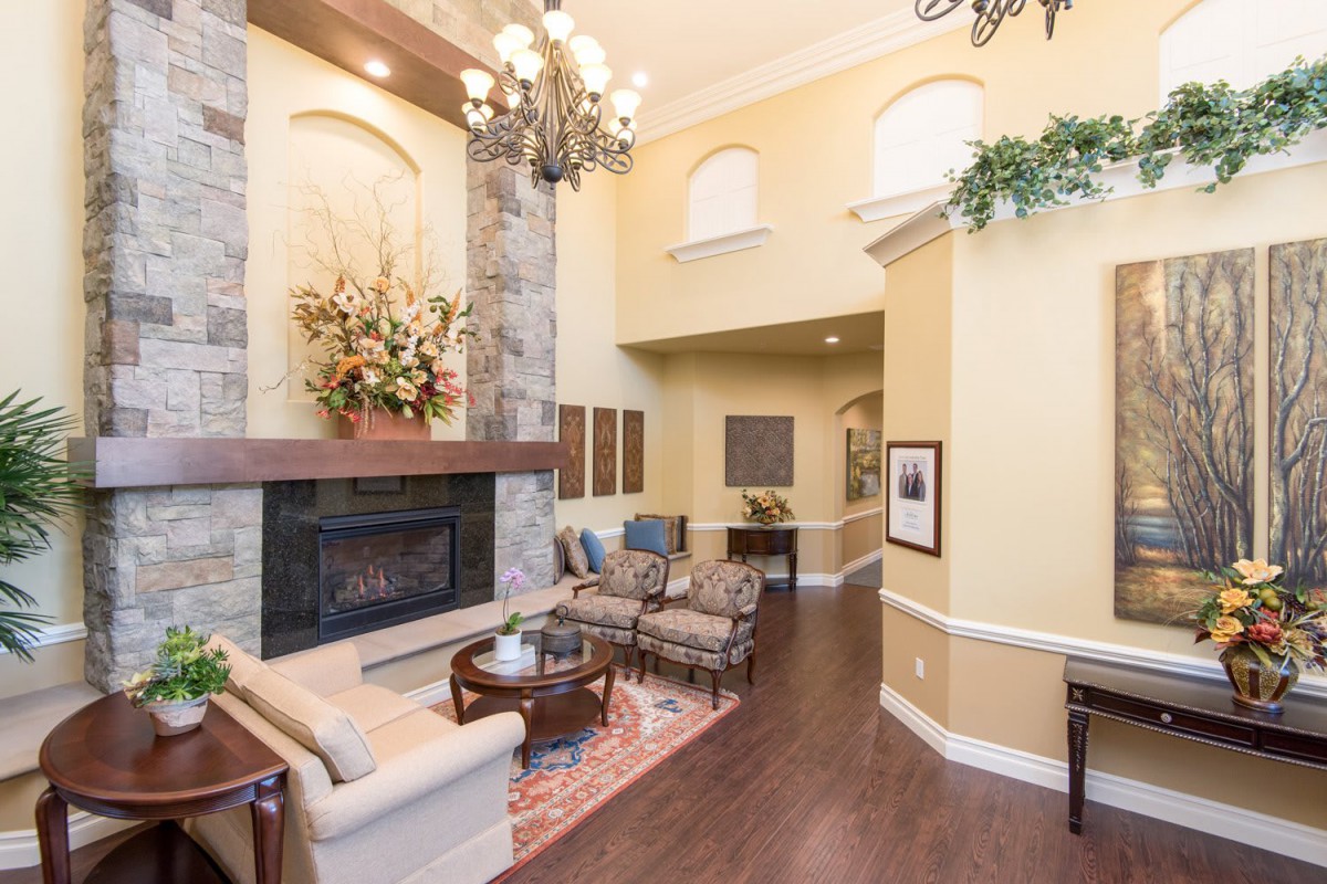 A spacious living room with a high ceiling, featuring a fireplace and elegant chandelier.