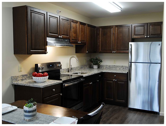 A modern kitchen with dark wood cabinets and stainless steel appliances.