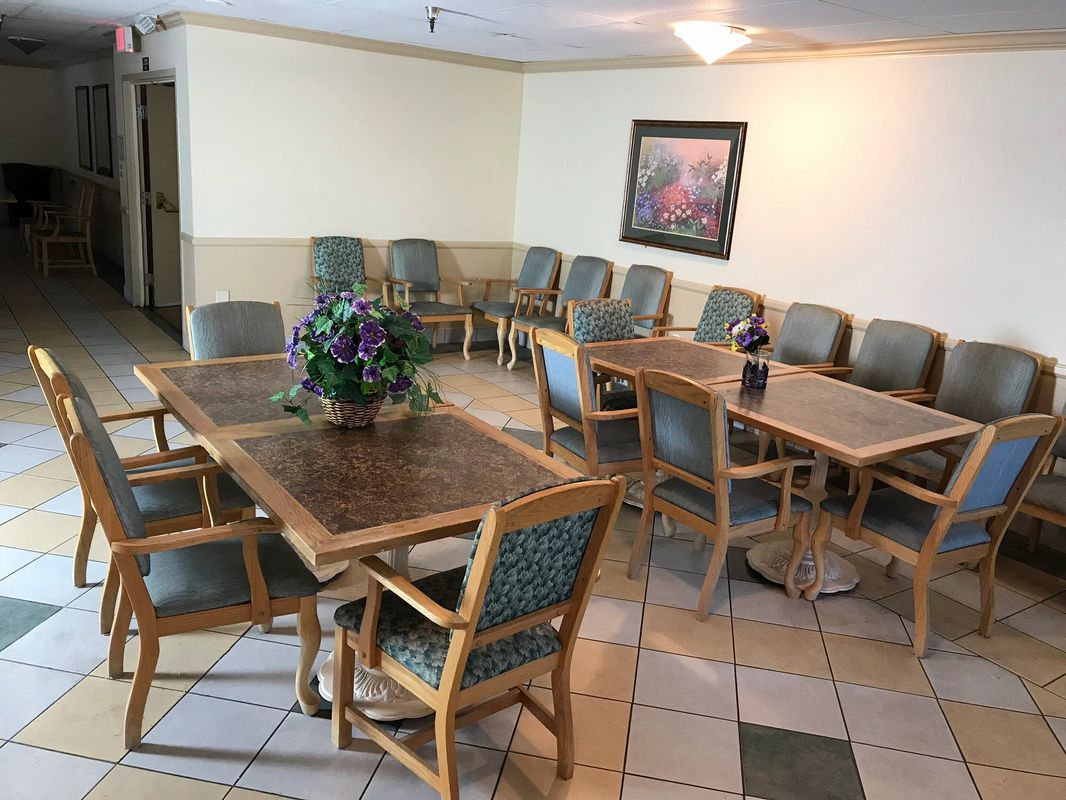 A waiting room with several chairs and tables arranged for seating, featuring a decorative painting on the wall.