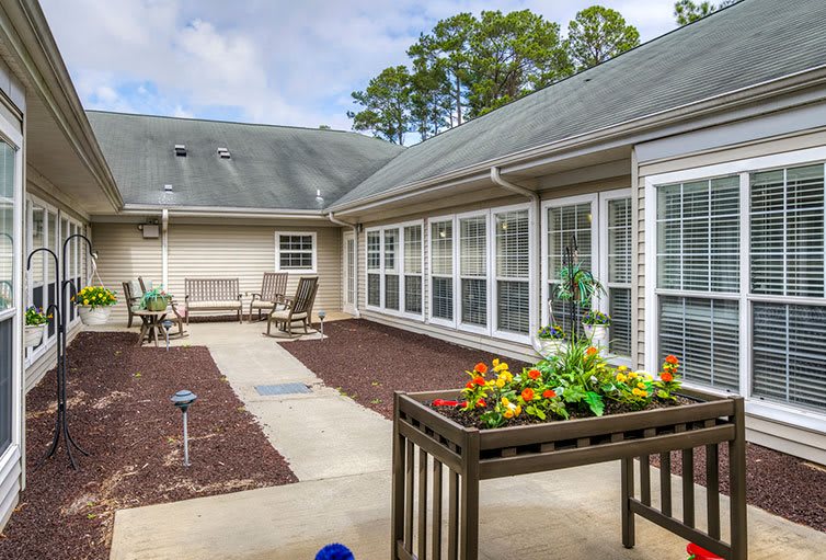 A cozy courtyard with seating, planters, and large windows.