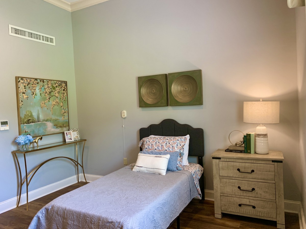A minimalist bedroom with a single bed, nightstand, and contemporary artwork.