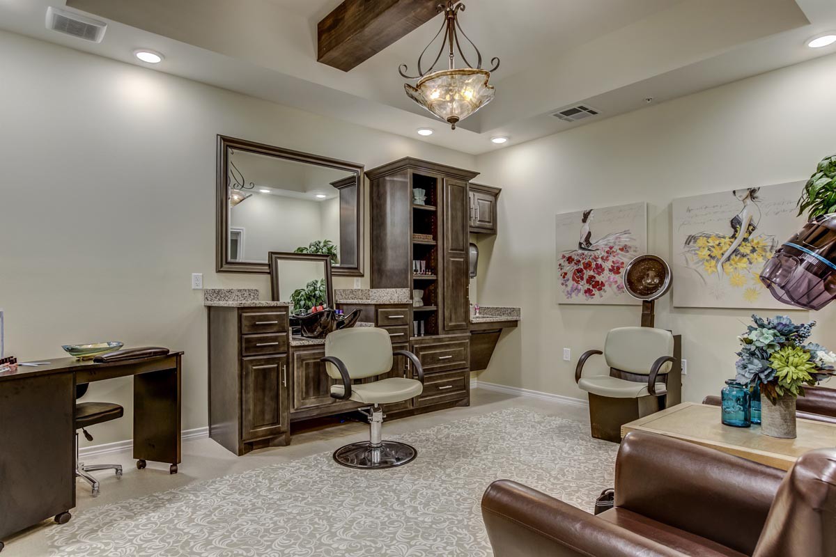 A modern salon interior with stylish furniture, mirrors, and a chandelier.