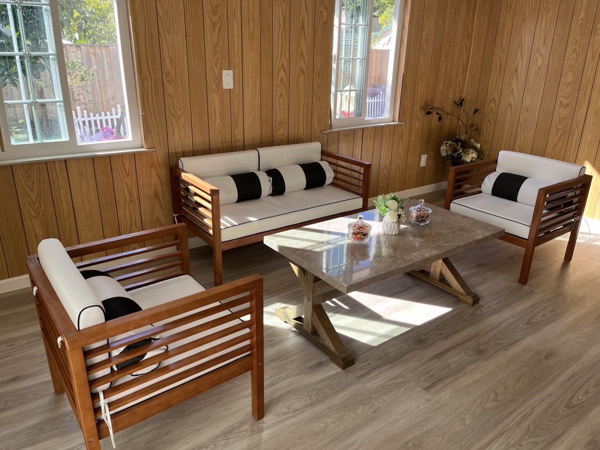 A cozy living room with wooden walls featuring modern furniture and a glass coffee table.