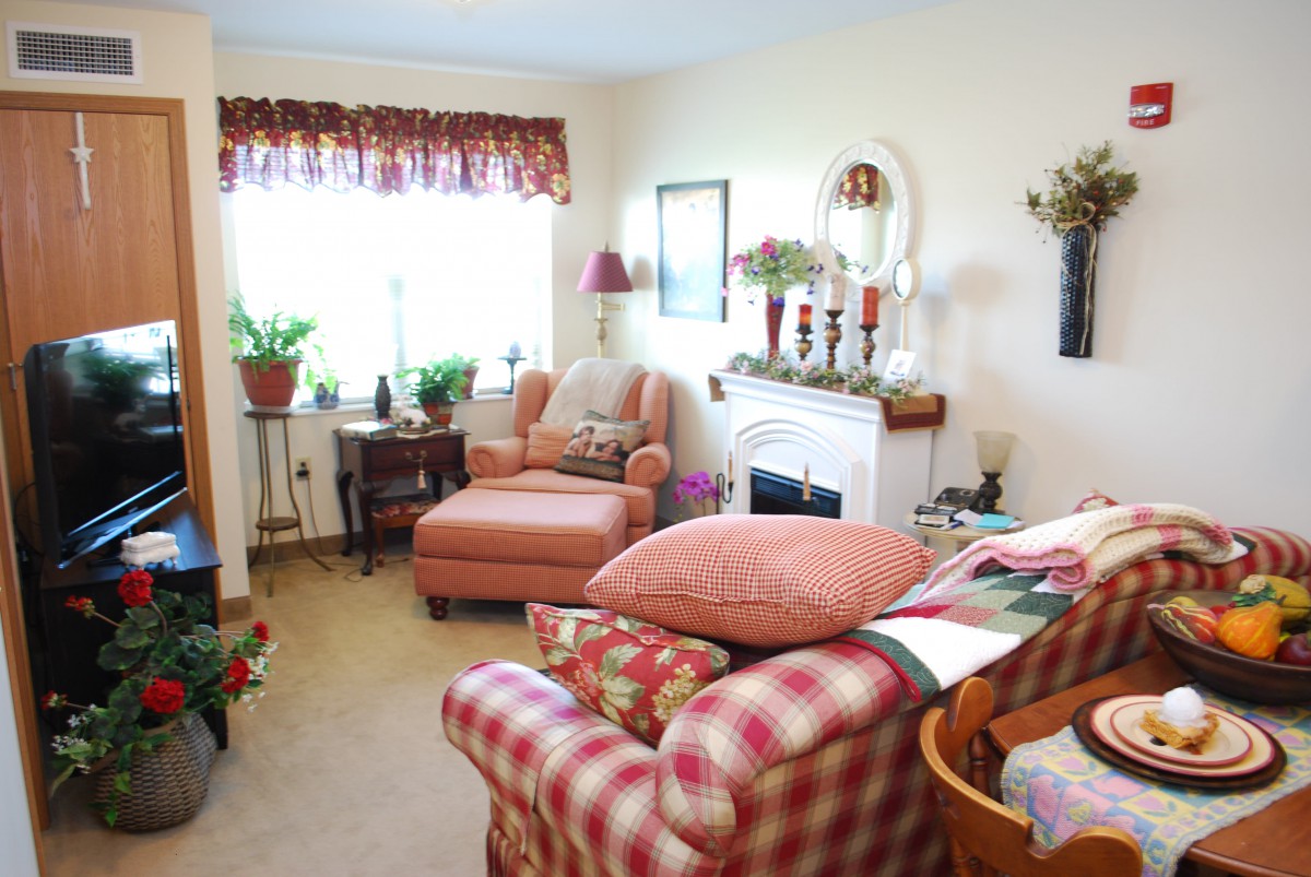 A cozy living room with colorful furniture and a variety of decorations, including plants and a fireplace.