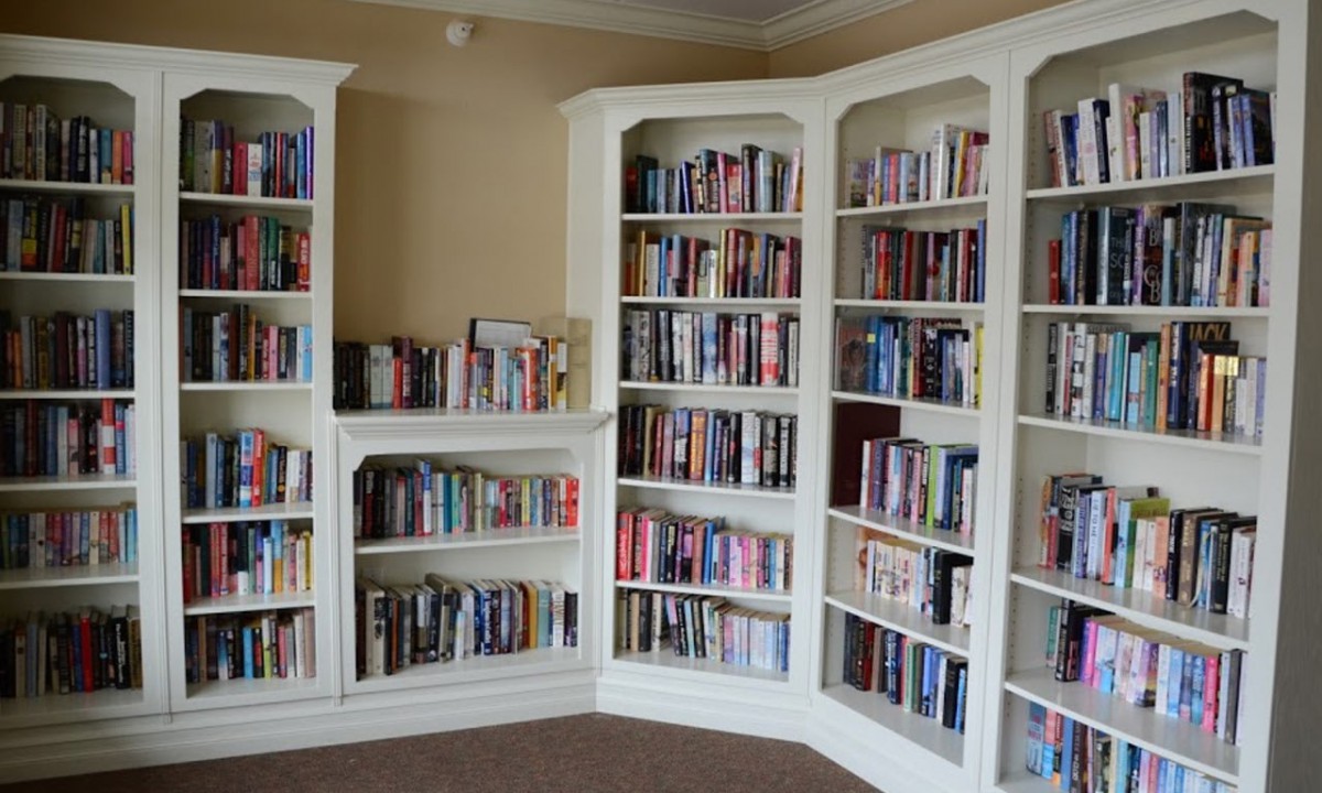 A cozy home library with white bookshelves filled with a variety of books.