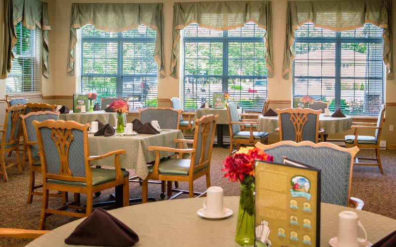 A cozy dining area with elegantly set tables and large windows.