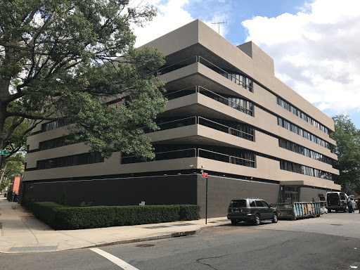 A modern multi-level building with a parking area in an urban setting.