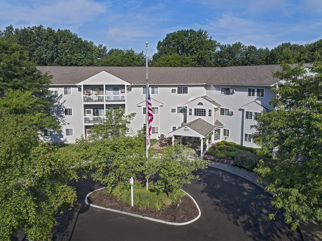 Aerial view of a residential apartment building surrounded by lush trees and landscaping.