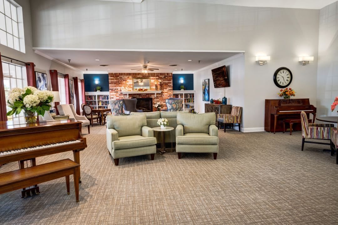 A cozy living room with two armchairs, a piano, and a fireplace.