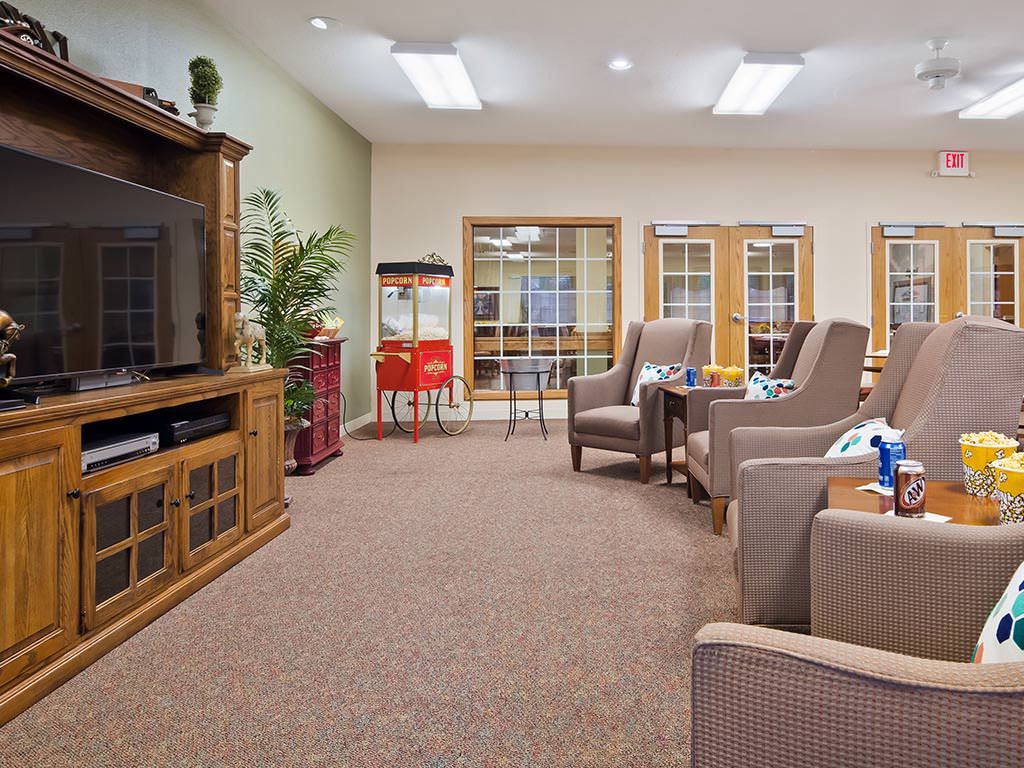 A cozy living room with a television, armchairs, and a popcorn machine.