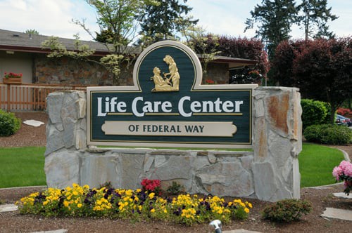 Sign for Life Care Center of Federal Way surrounded by flowers and trees.