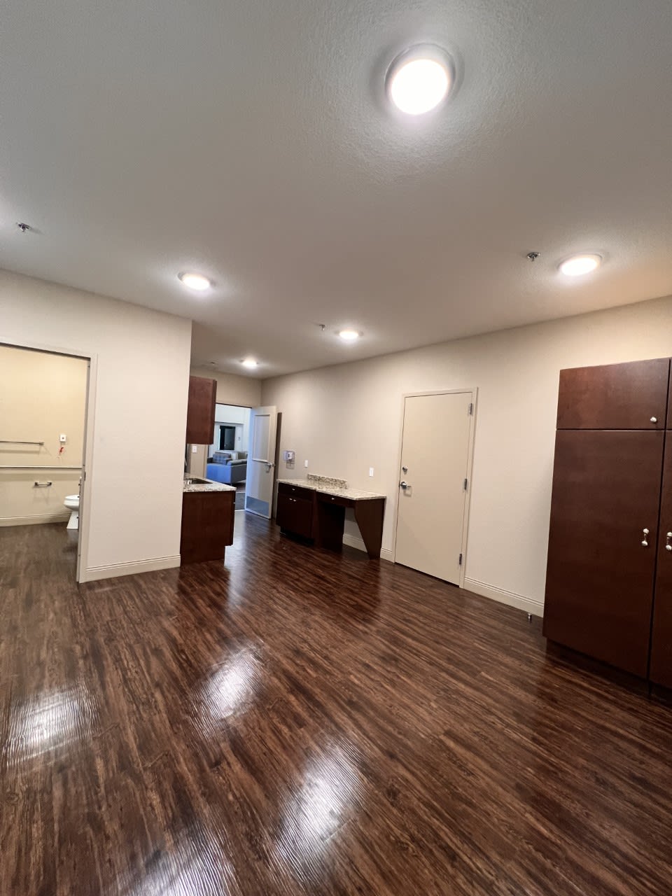 Spacious room with wooden floors and modern kitchen area.