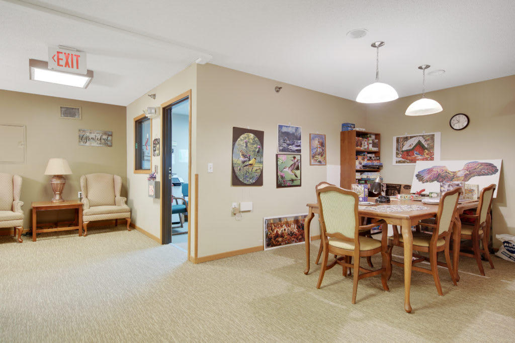 A cozy dining room with a wooden table, chairs, and decorative art on the walls.