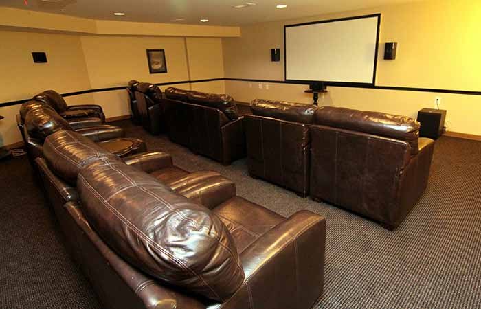 A cozy home theater room with leather sofas and a large projector screen.