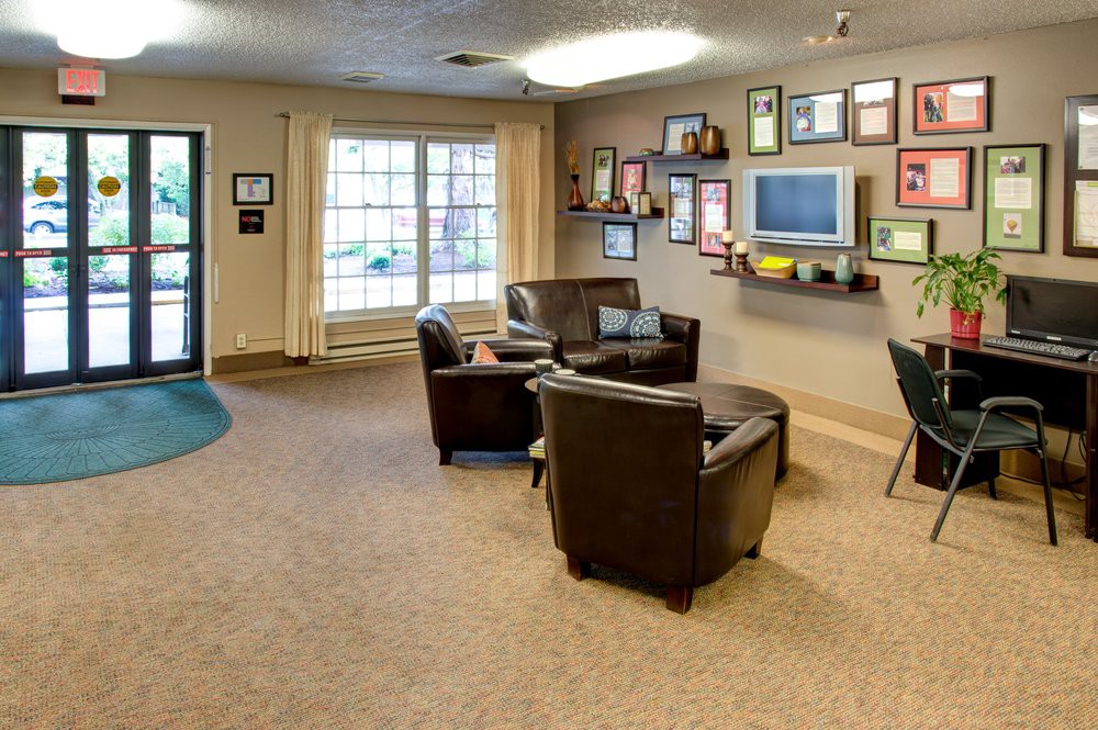 A cozy waiting room with leather chairs, a television, and framed certificates on the wall.