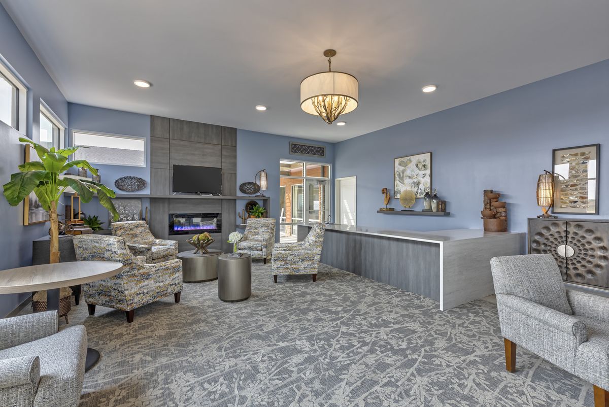 A modern living room with a stylish chandelier, comfortable seating, and a fireplace beneath a mounted television.