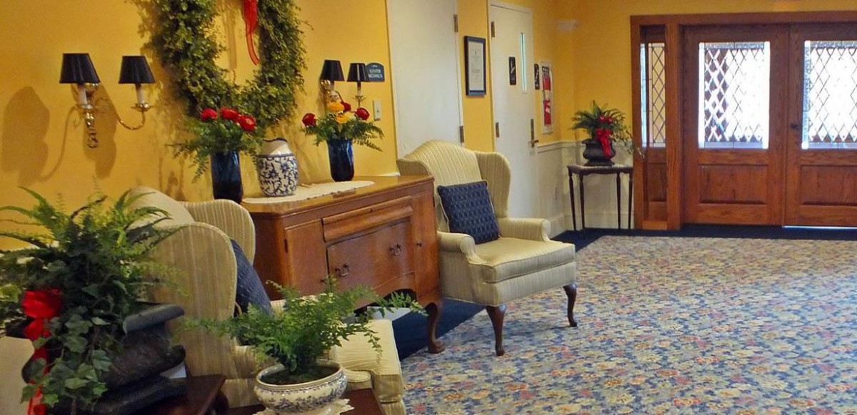 A warmly decorated room with yellow walls, featuring comfortable seating and plant accents.