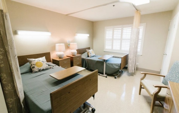 A clean and bright hospital room with two beds and a curtain divider.