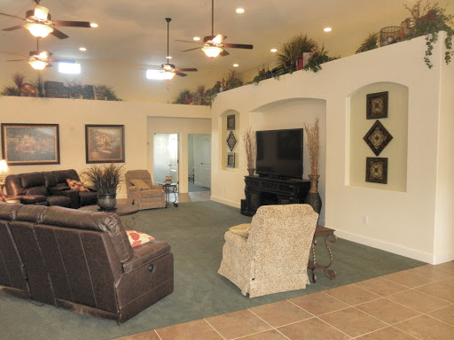 A spacious and well-decorated living room featuring comfortable seating, ceiling fans, and a television.