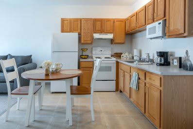 A cozy kitchen with wooden cabinets, equipped with essential appliances and a small dining area.