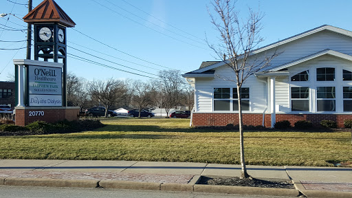 A view of a residential building with a neatly maintained lawn, a small tree in front, and clear blue skies.
