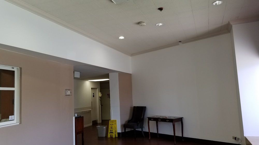 A lobby area with a chair, table, and caution sign.