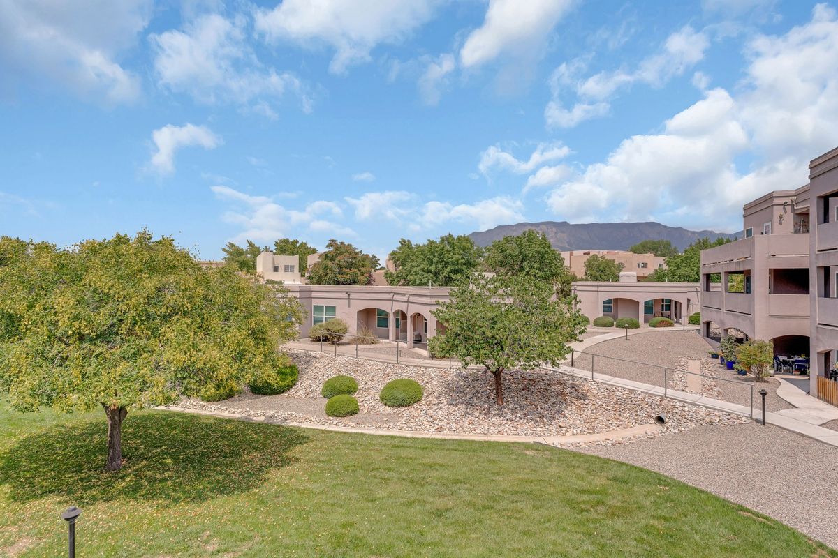 A scenic view of a building surrounded by lush greenery and a clear blue sky.