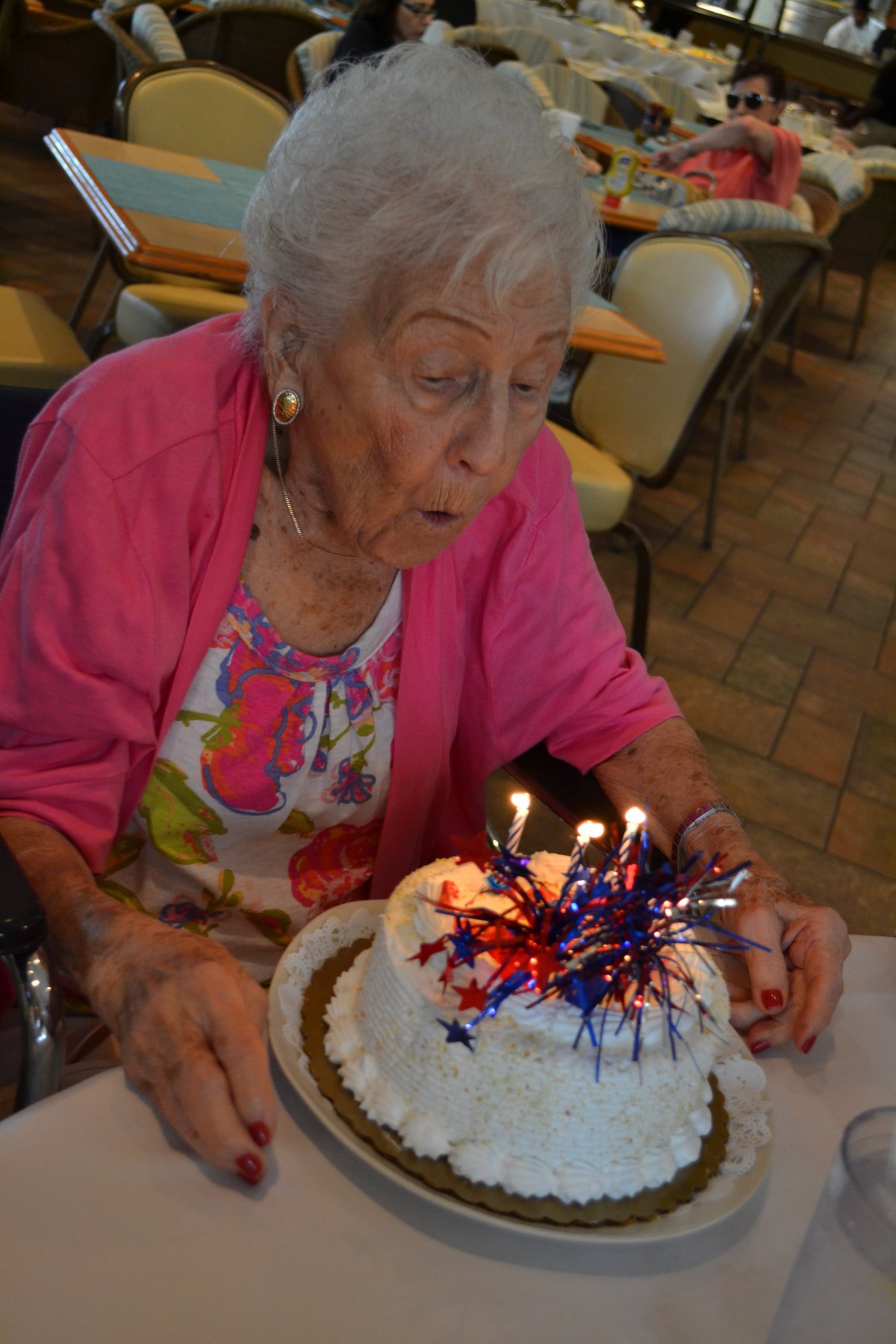 An elderly person celebrating a birthday with a decorated cake and candles.