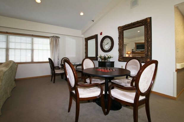 A well-furnished dining room featuring a round table with chairs, large mirrors on the walls, and elegant decor.