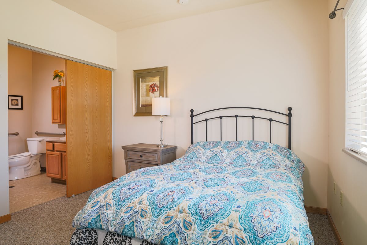 A cozy bedroom with a patterned bedspread, metal bed frame, and warm lighting.