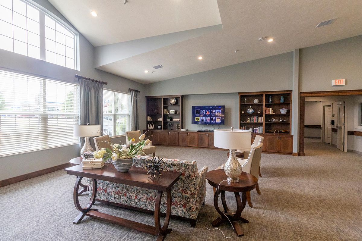 A spacious living room with large windows, comfortable seating, and built-in bookshelves featuring a modern TV setup.