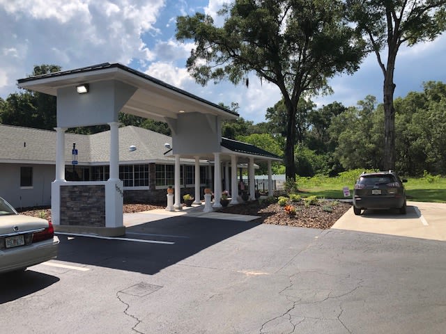 A building with a drive-thru on a sunny day surrounded by trees.