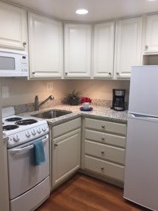A cozy kitchen with white cabinets and essential appliances.